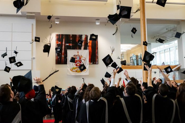 Photo of graduates tossing their graduation caps in the air