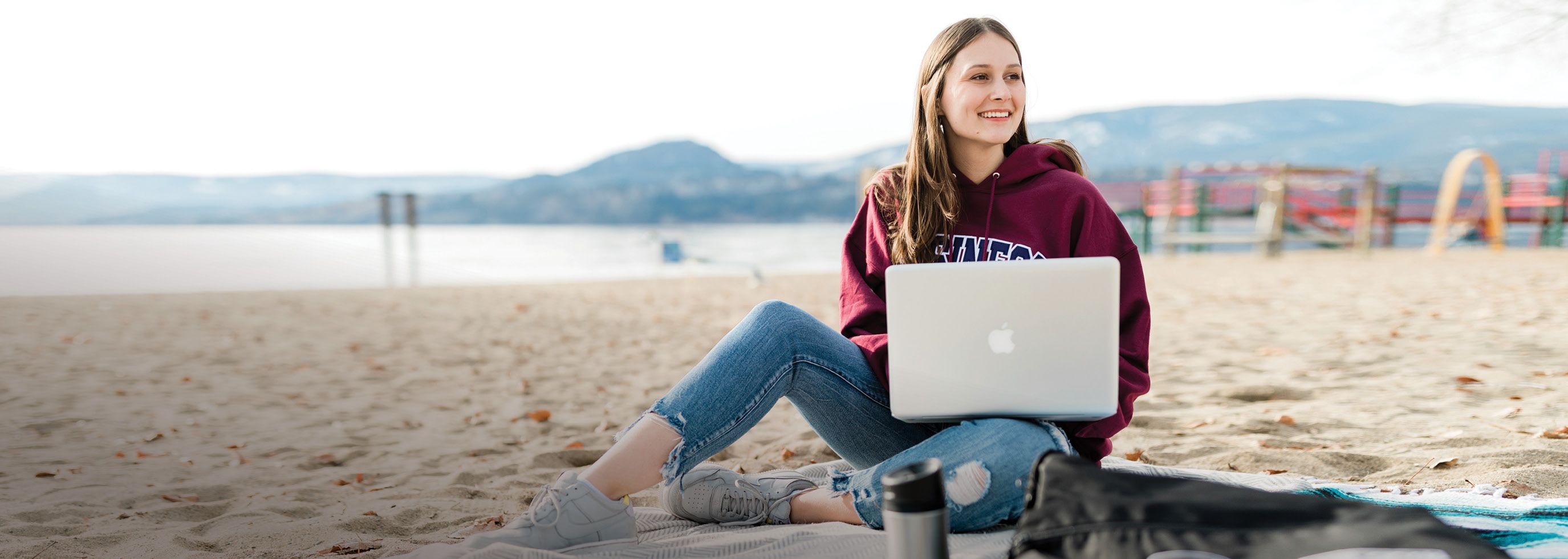 Students sitting on the beach with a laptop