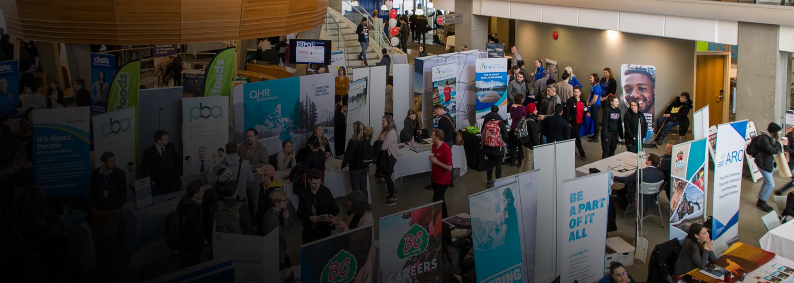 aerial view of booths set up in the Atrium with people interacting and mingling at Okanagan College's Annual Careers Expo and Employment Fair