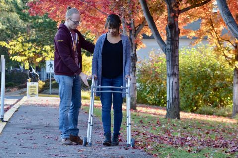 Student practises supporting a patient using a mobility aid