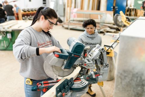 Two female Carpentry students cutting wood on chopsaw