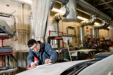 An Automotive Refinishing Prep Technician Apprenticeship student inspects the sanding job on a vehicle