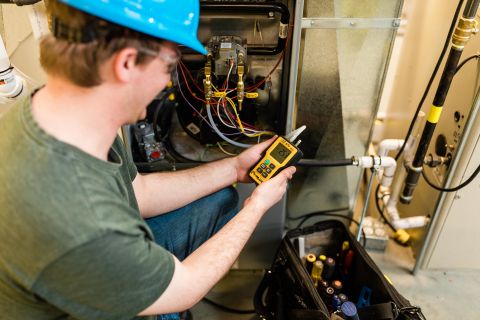 Plumbing apprentice uses digital instruments to measure the system performance.