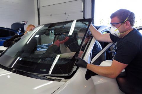 Automotive glass apprentices remove a windshield on a vehicle.