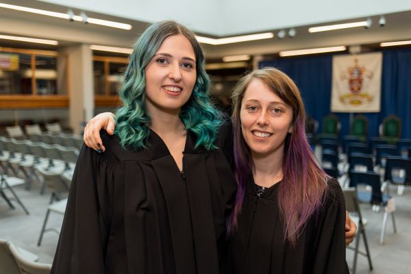 Two graduates wearing gowns at the Trades Commencement
