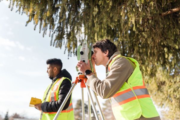 Civil Engineering students use surveying equipment in the field as part of classwork.
