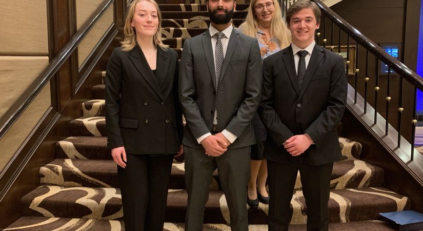 3 students wearing suits standing on a stairwell