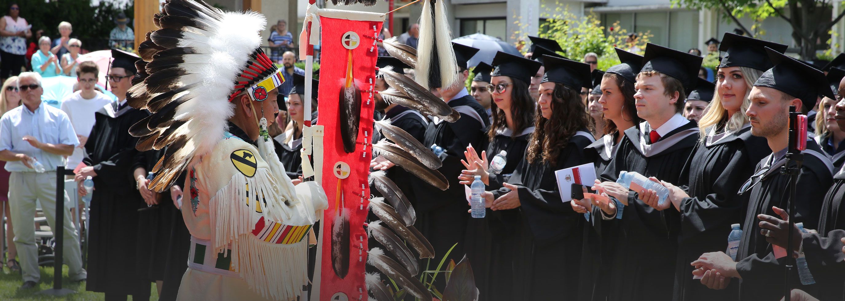 Indigenous elder carrying the Eagle Feather Staff at a convocation ceremony