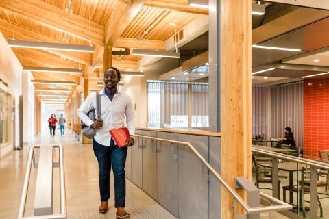 male student walking with books inside building