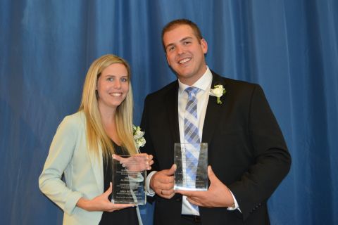 two alumni posing with awards