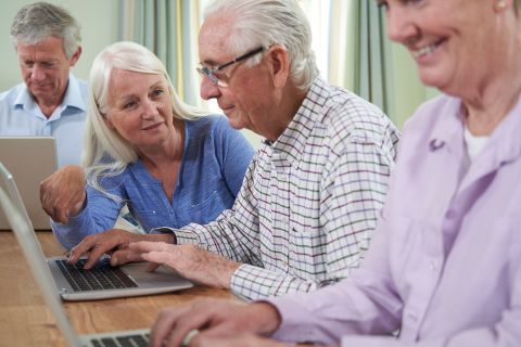 four senior citizens working on computers