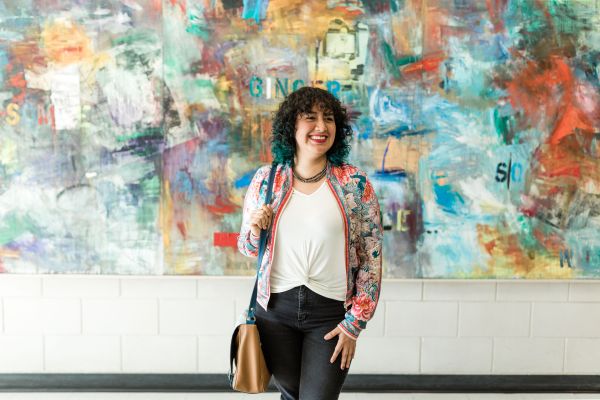Advanced Certificate in Communications student stands in front of a colourful painting