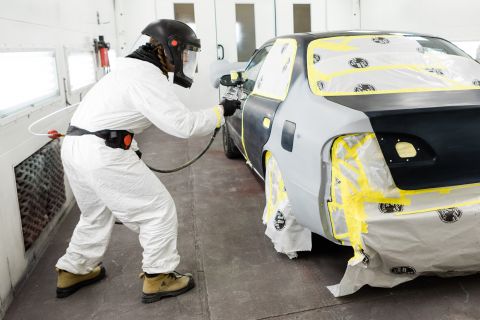 Collision Repair student carefully applies paint to the body of a vehicle in a spray booth