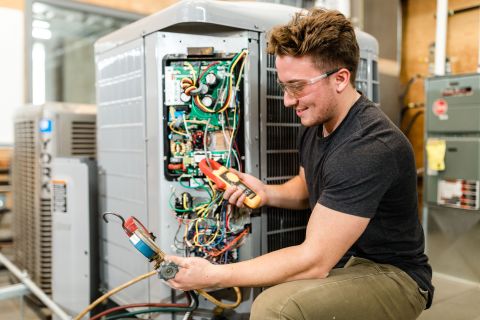 Refrigeration and Air Conditioning student uses digital instruments to measure the operation of an AC unit