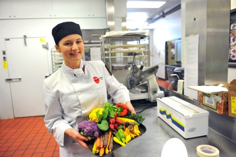 Culinary Arts student holding a platter with a colourful array of vegetables.