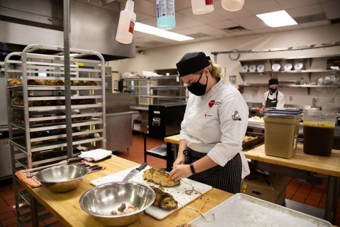 Culinary Arts student chops turkey on a cutting board in the Okanagan College kitchen