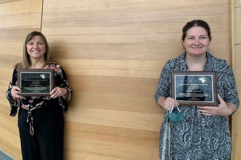 Kerry Rempel and Kyleen Myrah hold up conference plaques in the Centre for Learning