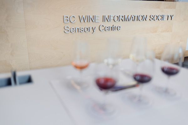 BC Wine Sensory Centre sign with wine glasses on a table in front of the sign