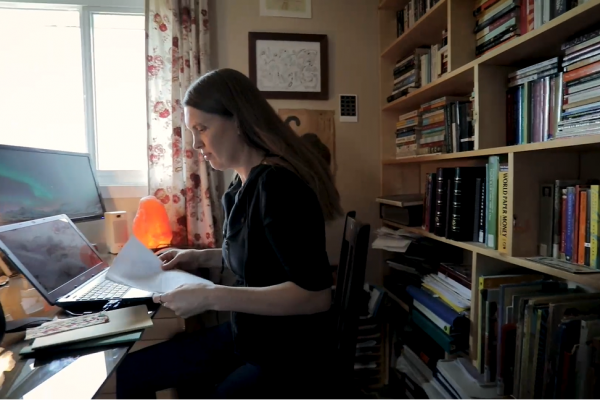English Professor Hannah Calder reads while sitting in her home office by a window