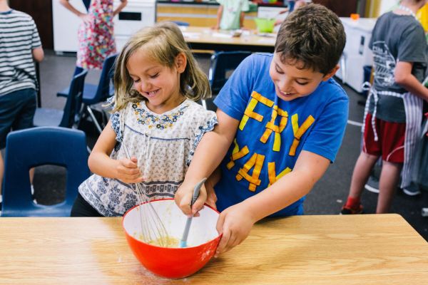 a girl and boy mixing ingredients in a mixing bowl