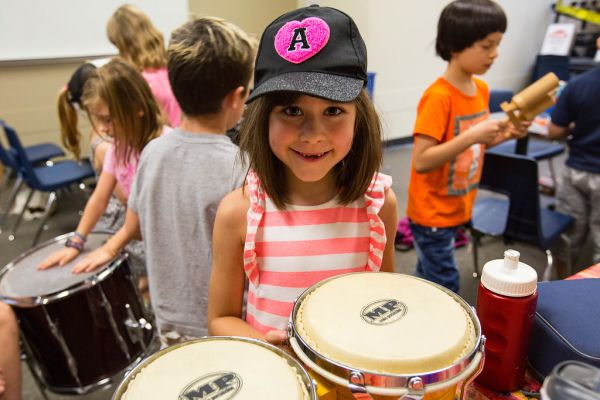 a little girl holding a drum set
