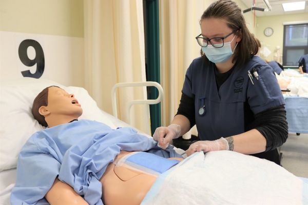 Practical Nursing student in the training lab doing a procedure on a mannequin