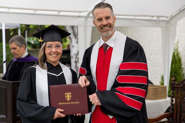 Student and Neil Fassina, OC President, both holding a parchment folder at a convocation ceremony