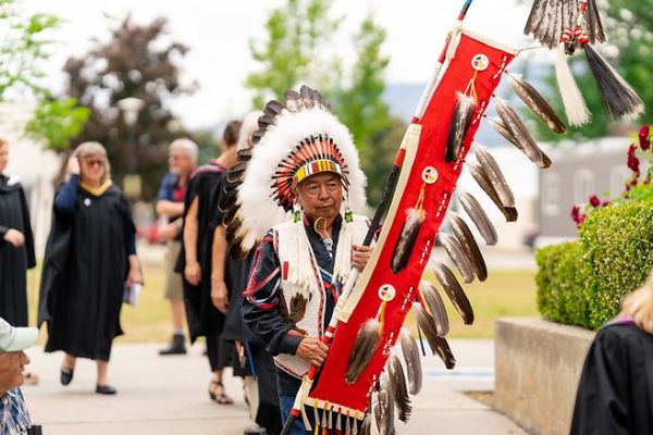 Richard Jackson Junior, from Lower Nicola Indian Band, carries the Eagle Staff at the Kelowna campus convocation on June 10, 2023