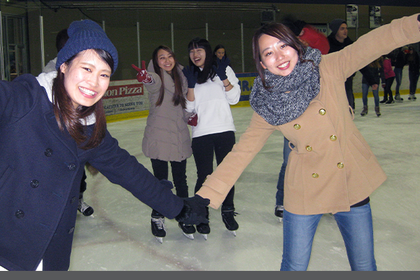 2 smiling students holding hands on skates 