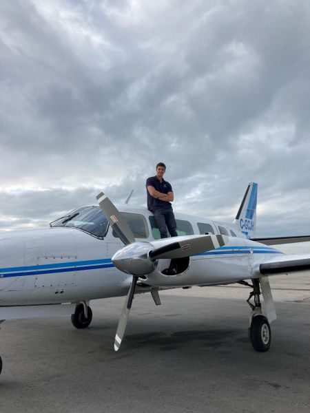 OC alum Joey Rood standing by an airplane