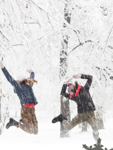 2 students dressed in winter clothes jumping for joy 