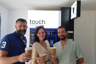 Yaroslav Khaynas (left) and his wife Olena (middle) stand with Eugene Pavlov (right) in front of their Touch Coffee machine at OC’s Kelowna campus. 