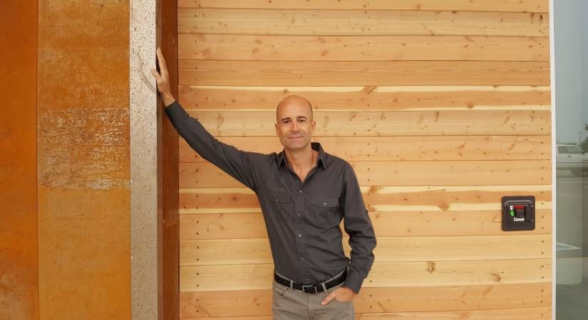 SCMT Professor Brian Rippy leans on a sustainable wood building