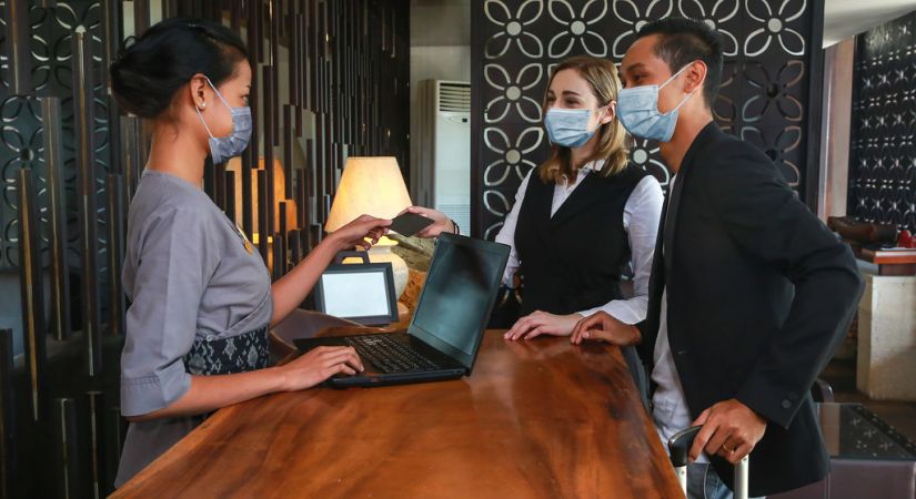 Two people checking into a hotel handing a credit card to hotel staff standing at a desk