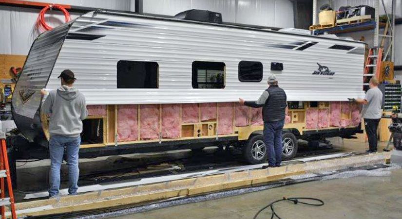 Three RV Service Technician students installing insulation on an RV in the shop