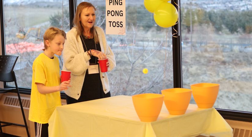 A young child plans ping pong toss with their parent.