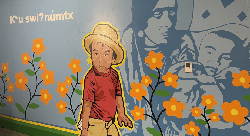 painted mural with blue background, orange flowers, a young boy, and a woman and baby
