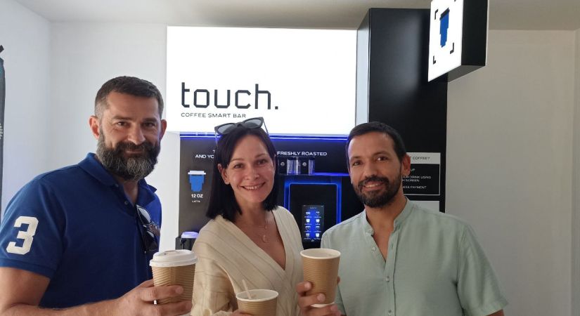 Yaroslav Khaynas (left) and his wife Olena (middle) stand with Eugene Pavlov (right) in front of their Touch Coffee machine at OC’s Kelowna campus. 